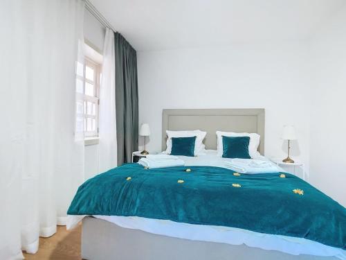 a bedroom with a large bed with blue sheets and pillows at Aquae Flaviae Urban Stay - Charm in Chaves