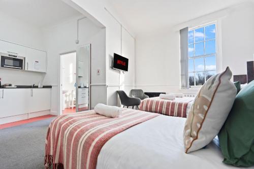 a hotel room with two beds and a kitchen at Vibrant, spacious studio with Parking and Netflix in Dudley