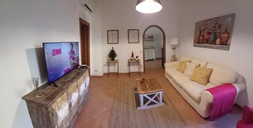 a living room with a couch and a flat screen tv at KiKi House Bracciano in Bracciano