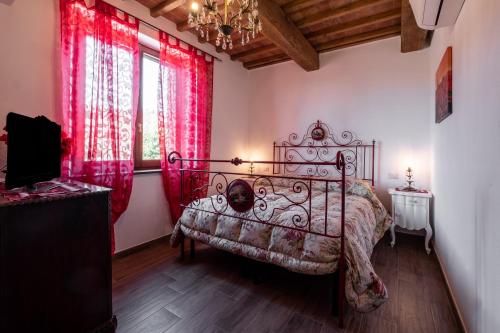 a bedroom with a bed with red curtains and a chandelier at Appartamento Rosso - Monte Crespini in Manciano