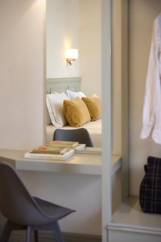 a mirror reflection of a bed with pillows and a chair at AthenSun Luxury Suites in Athens