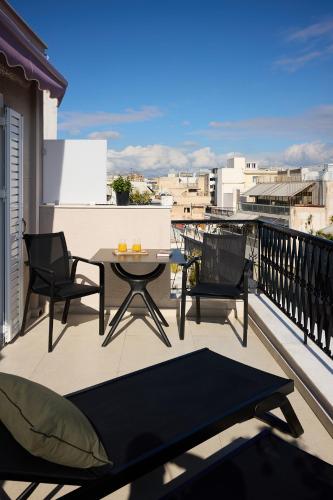 a patio with a table and chairs on a balcony at AthenSun Luxury Suites in Athens