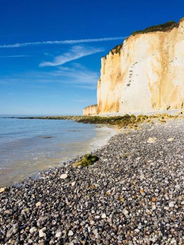 a rocky beach next to a white cliffs at La Villa du Clos Normand Les Petites Dalles - Maison d'hôtes in Saint-Martin-aux-Buneaux