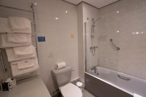 a bathroom with a toilet and a shower with towels at Skipton Hotel - formerly known as Hotel Rendezvous-Skipton in Skipton