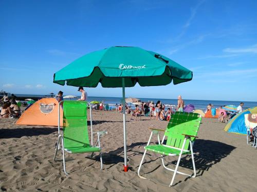 マル・デル・プラタにあるCielo azúlのビーチでの緑の椅子2脚とパラソル1本