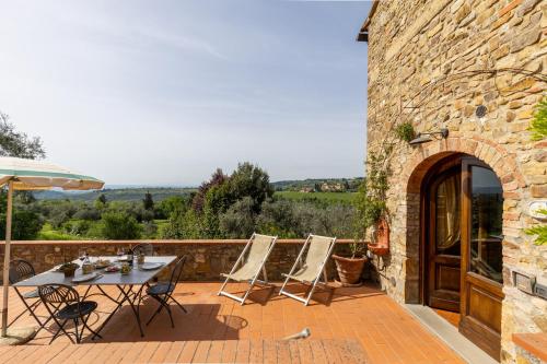 a patio with chairs and a table and an umbrella at Podere San Bartolo- Fienile in Barberino di Val dʼElsa