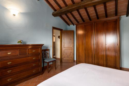 a bedroom with a bed and a wooden dresser at Podere San Bartolo- Fienile in Barberino di Val dʼElsa
