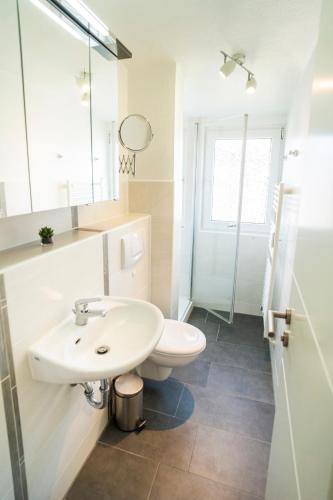 a white bathroom with a sink and a toilet at Duhner Ausblick mit Balkon in Cuxhaven
