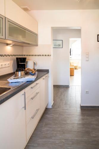 a kitchen with white cabinets and a counter top at Duhner Ausblick mit Balkon in Cuxhaven