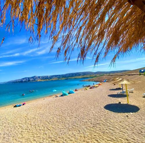 a beach with umbrellas and people in the water at Wohnung Katarina Auf Der Insel Pag in Zubovići