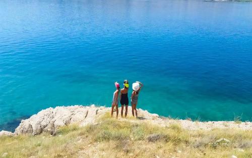 three people standing on a hill near the water at Wohnung Katarina Auf Der Insel Pag in Zubovići