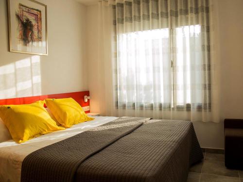 ein Schlafzimmer mit einem Bett mit gelben Kissen und einem Fenster in der Unterkunft Ferienhaus in Torroella De Montgrí mit Privatem Pool in Torroella de Montgrí