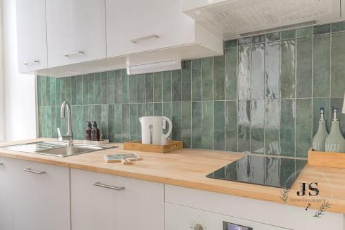 - une cuisine avec des placards blancs et un mur carrelé vert dans l'établissement Le Dauphiné studio climatisé, à Lyon