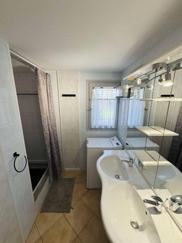 une salle de bain blanche avec un lavabo et un miroir dans l'établissement Les Cyprés, à Saintes-Maries-de-la-Mer