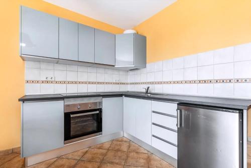 a kitchen with white cabinets and a sink and a dishwasher at Sunny Escape in Costa Calma
