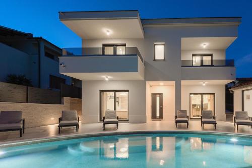 a house with a swimming pool in front of a building at Villa Cascada in Muntić
