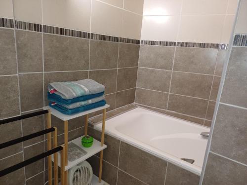 une salle de bain avec baignoire et douche avec serviettes dans l'établissement Maison de village au centre de Thuir jusqu'à 5 personnes et 1 bébé, à Thuir
