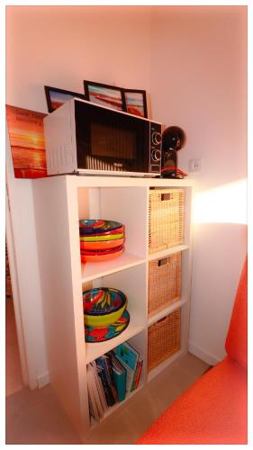 une étagère blanche avec de la vaisselle et un micro-ondes dans l'établissement Studio Cabine neuf 4 personnes - Bormes les Mimosas - 300m de la plage de La Favière, à Bormes-les-Mimosas
