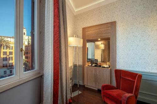 a room with a red chair and a window at The Inn at the Spanish Steps Luxury Collection - The Inn at the Spanish Steps in Rome