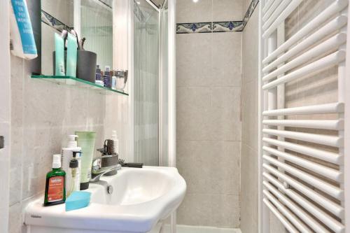 une salle de bain blanche avec un lavabo et un miroir dans l'établissement appartement cosy Montmartre, à Paris