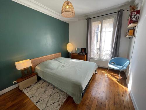 une chambre avec un lit et une chaise bleue dans l'établissement appartement cosy Montmartre, à Paris