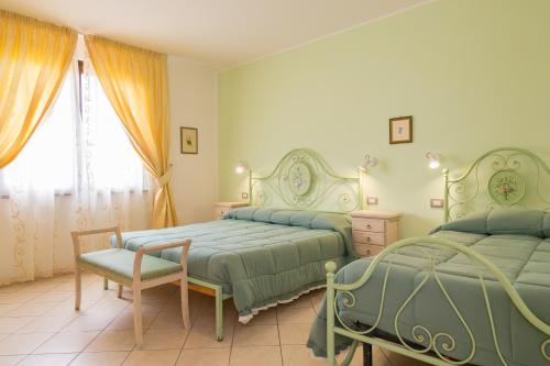 een slaapkamer met twee bedden en een stoel en een raam bij Il Girasole - Malva in Venturina Terme