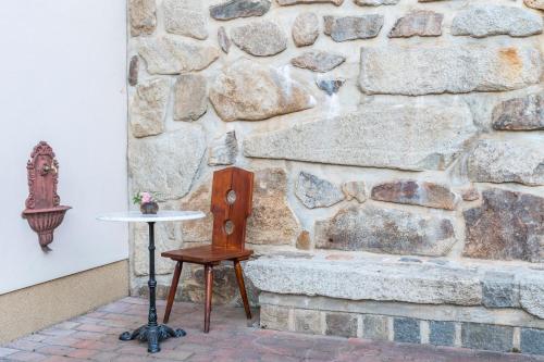 a table and chair next to a stone wall at Rožmberk Royale Pension in Rožmberk nad Vltavou