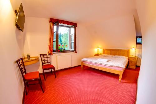 a bedroom with a bed and two chairs and a window at Rožmberk Royale Pension in Rožmberk nad Vltavou