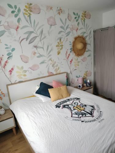 - une chambre avec un lit orné de fleurs sur le mur dans l'établissement Nid douillet à l'orée des bois à 20 min du circuit des 24h du Mans, à La Suze-sur-Sarthe