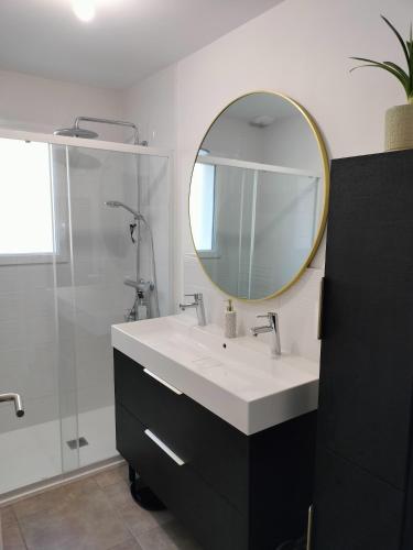 une salle de bain avec un lavabo et un miroir dans l'établissement Nid douillet à l'orée des bois à 20 min du circuit des 24h du Mans, à La Suze-sur-Sarthe