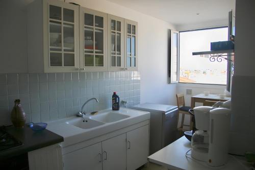 une cuisine blanche avec un évier et une fenêtre dans l'établissement Appartement Au Sud Avec Vue Bassin, à Arcachon