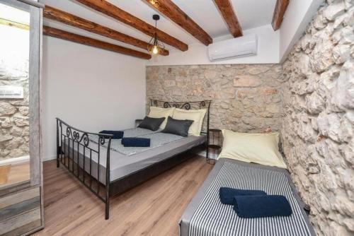 a bedroom with two beds and a stone wall at Villa Karla in Novalja
