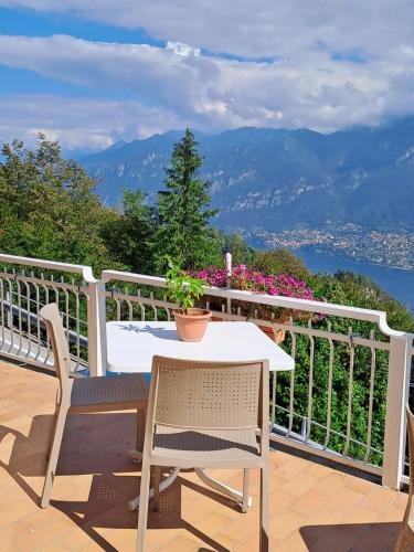 a table and chairs on a balcony with a view of the mountains at Hotel Mirabeau in Bellagio