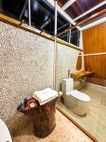 a bathroom with a toilet and a glass wall at Pousada Beira da Mata-Jalapão in Mateiros