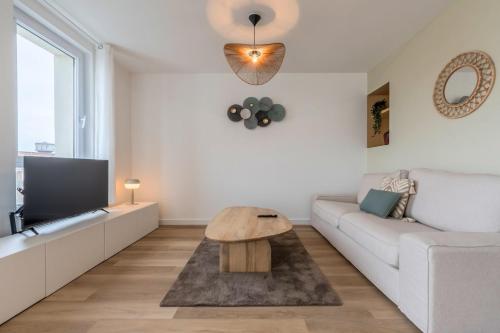 un salon avec un canapé blanc et une table dans l'établissement Appartement 2 chambres avec parking et balcon, à Marcq-en-Barœul