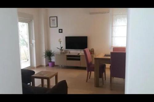 a living room with a table and a television at Family Holiday Home in Turanj