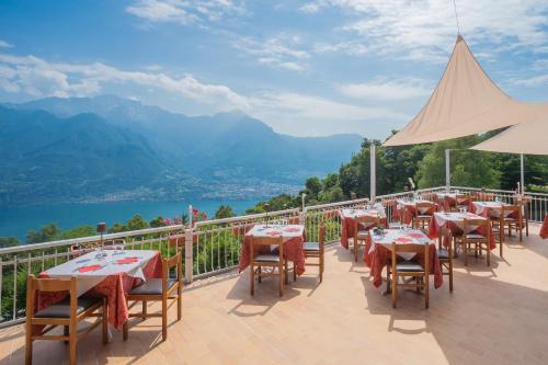 a restaurant with tables and chairs on a balcony with mountains at Hotel Mirabeau in Bellagio