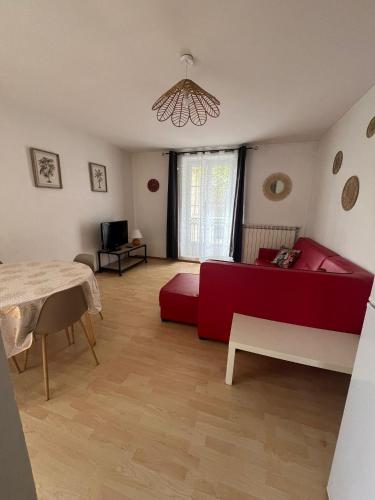 un salon avec un canapé rouge et une table dans l'établissement Les Platanes - Michel Ange, à Lamalou-les-Bains