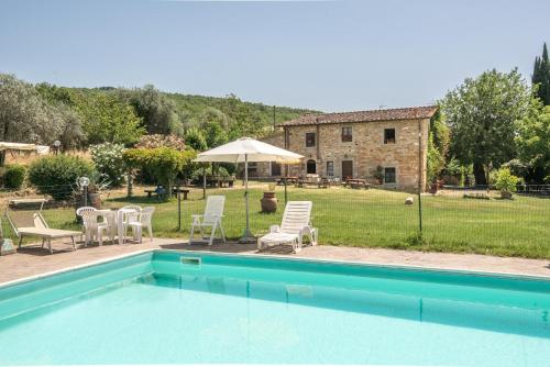 a pool with chairs and an umbrella and a house at Poggio Primo - Bilocale Vermiglio in Castiglion Fibocchi