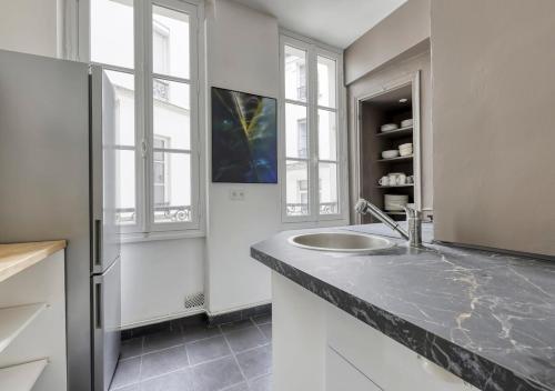 une salle de bain avec un lavabo et deux fenêtres dans l'établissement Spacious Typical Parisian Flat - Paris Le Marais, à Paris