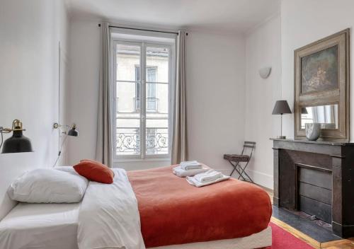 - une chambre avec un grand lit et une cheminée dans l'établissement Spacious Typical Parisian Flat - Paris Le Marais, à Paris