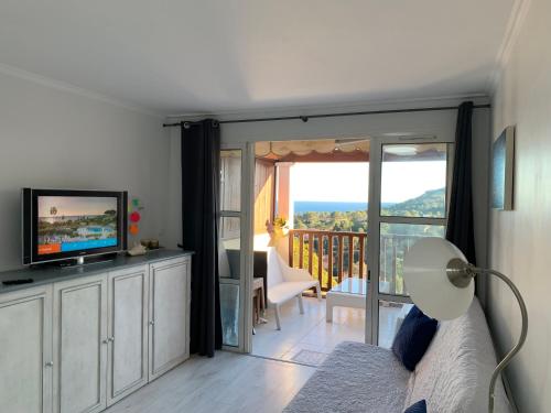 une chambre avec un lit et une télévision et un balcon dans l'établissement Cap Esterel - endroit magique entre mer et l'Esterel - agréable 2 pièces au gout du jour vue mer, à Saint-Raphaël