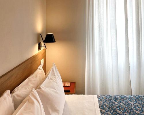 a bedroom with a bed with white pillows and a window at AmiRooms Affittacamere in Siena