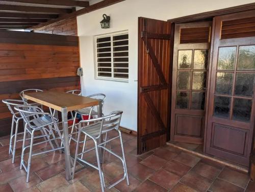 a patio with a table and chairs and a door at Appartement moderne au Moule avec terrasse et jardin in Le Moule