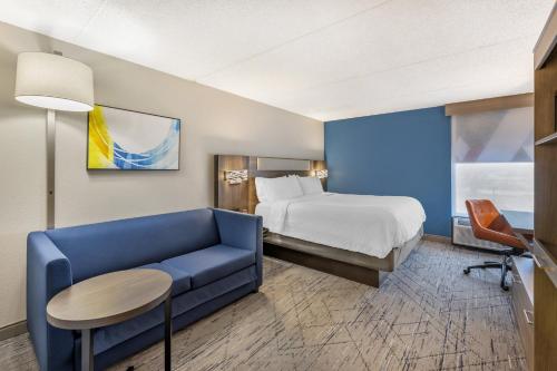 a hotel room with a bed and a blue couch at Holiday Inn Express Crestwood by IHG in Crestwood