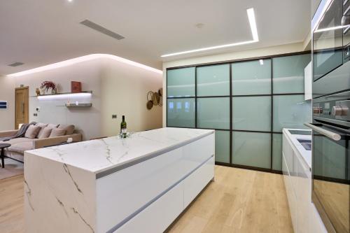 a kitchen with white countertops and a living room at Modern Two Bedroom Apartment in Valletta in Valletta