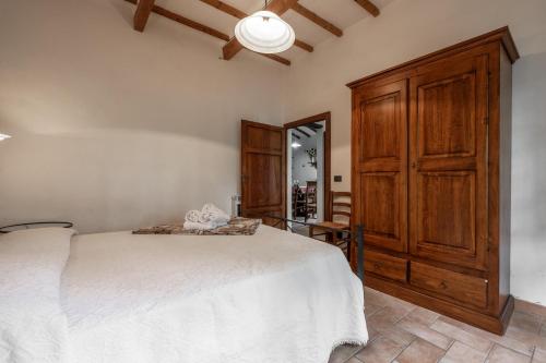 a bedroom with a white bed and a wooden cabinet at Piamperugino in Arcidosso