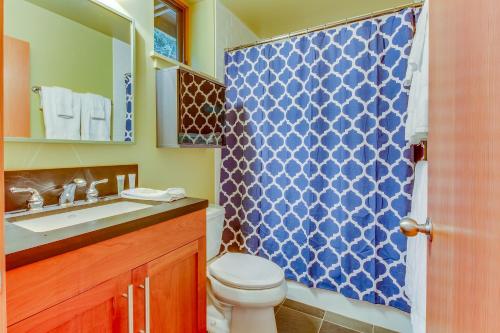 a bathroom with a toilet and a blue shower curtain at Driftwood Retreat in Anacortes