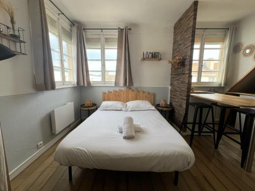 une chambre avec un lit, un bureau et des fenêtres dans l'établissement Le Marin, à Calais