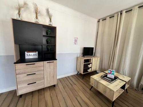 - un salon avec une télévision et une commode en bois dans l'établissement Le Marin, à Calais